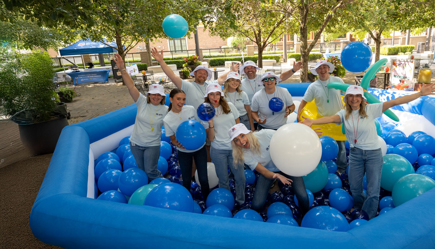The Marathon Pipe Line team standing in an inflatable pool with balloons, laughing and smiling after a volunteer event