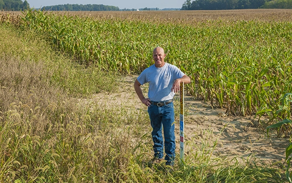 A farmer standing in a field with a smile on his face